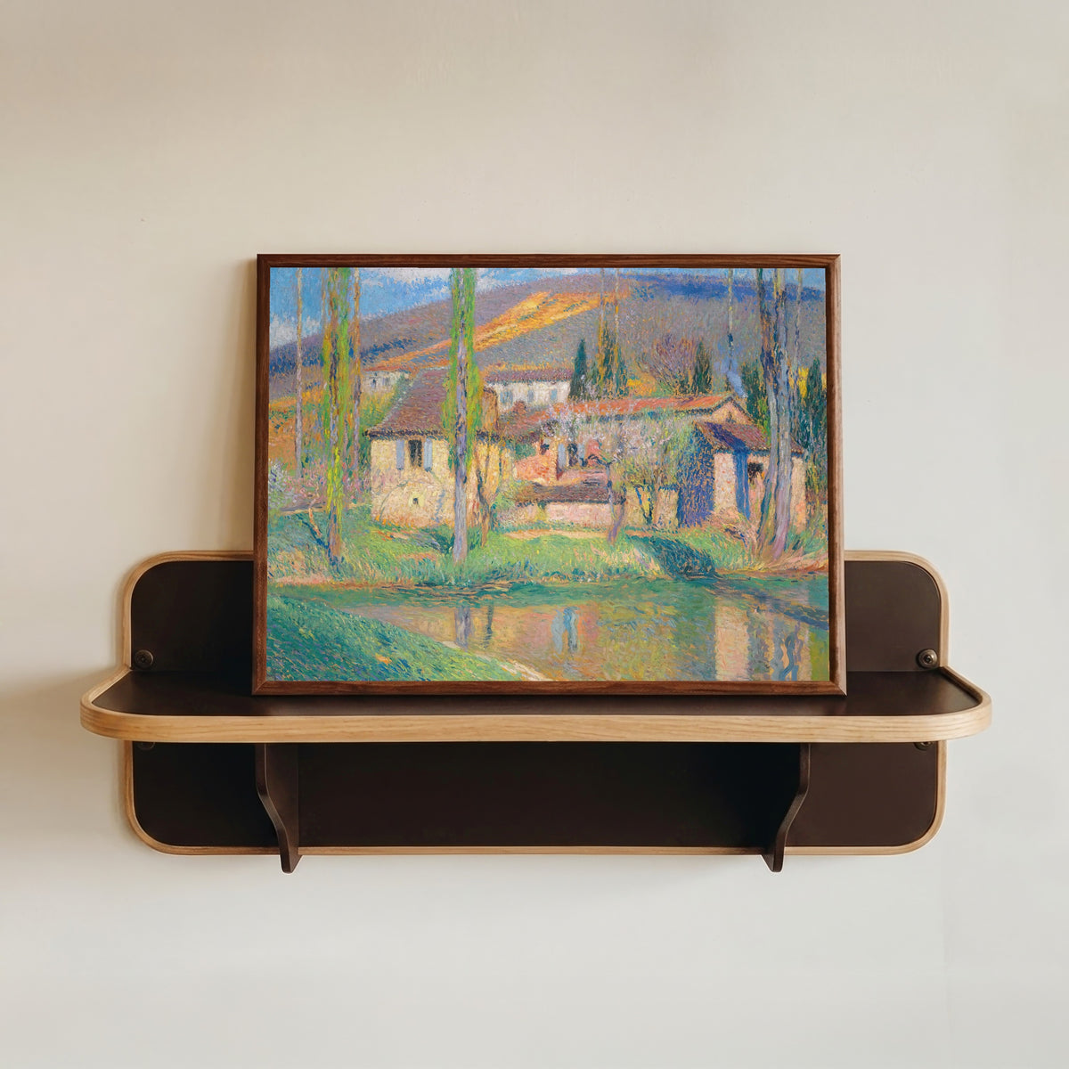 Framed art print of Labastide-du-Vert (Houses Reflected in the River) by Henri Martin, in a dark wood frame resting on a wall shelf