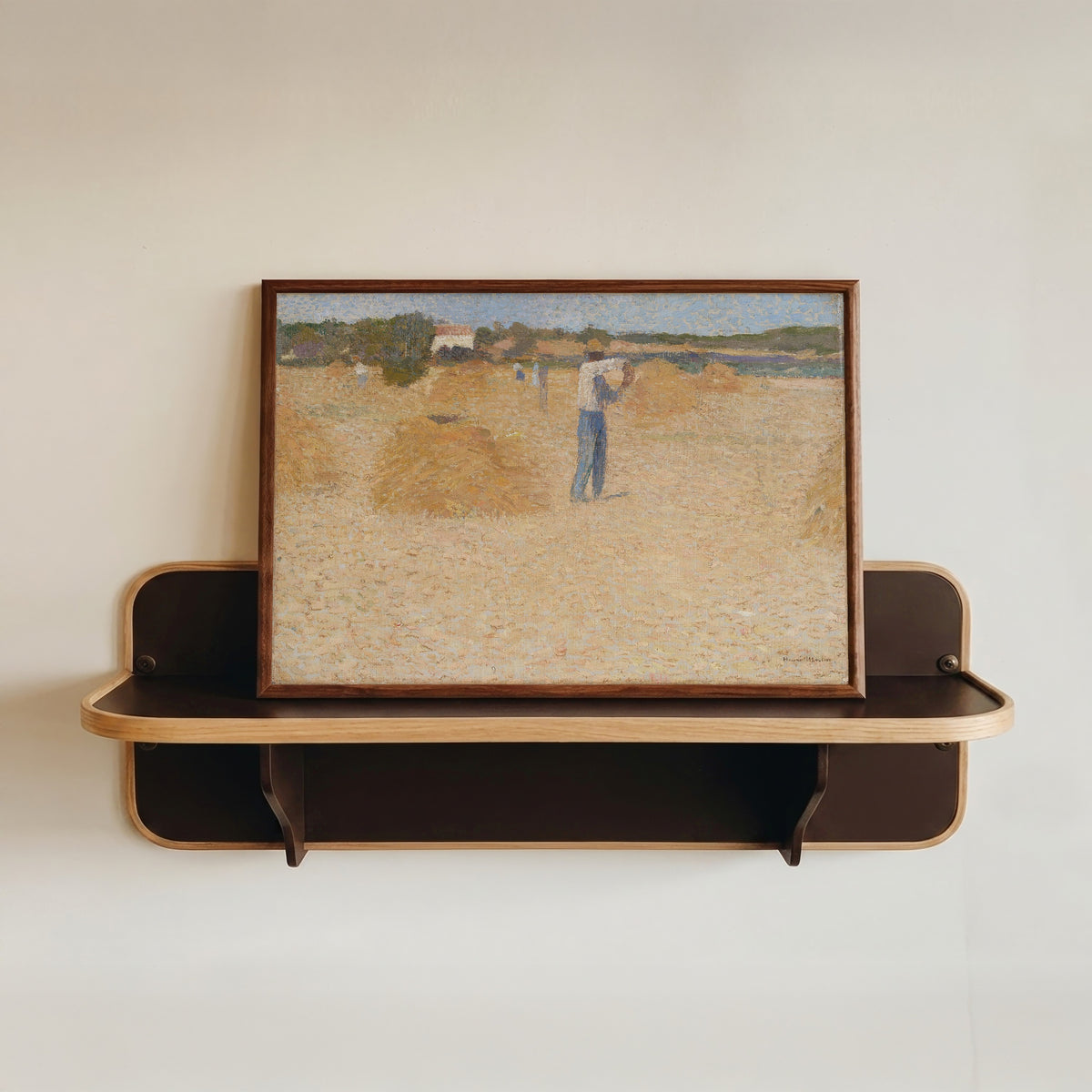 Framed art print of Les Moissons de blé by Henri Martin, in a dark wood frame resting on a wall shelf
