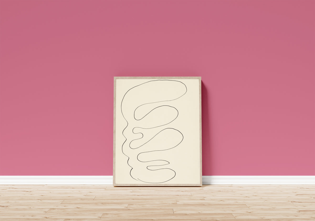 Framed art print of Arabesque by Henri Matisse, in a light wood frame leaning on a pink wall above a wooden floor