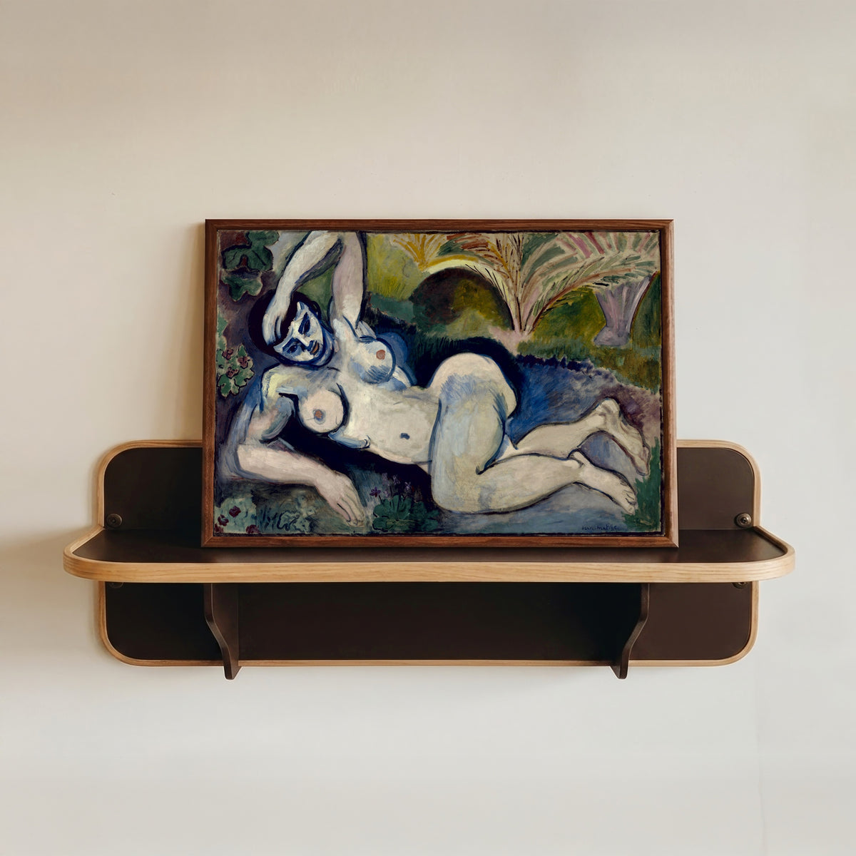 Framed art print of Blue Nude (Souvenir de Biskra) by Henri Matisse, in a dark wood frame resting on a wall shelf