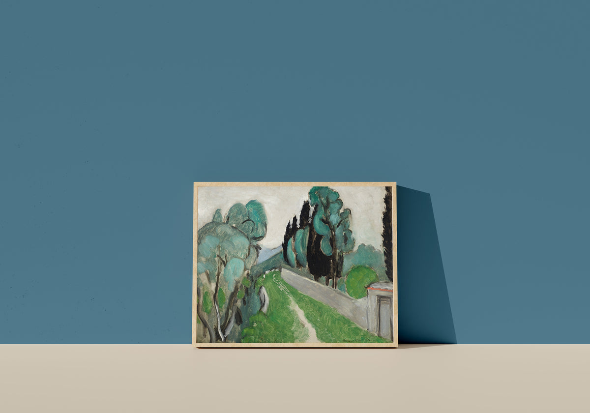 Framed art print of Landscape with Cypresses and Olive Trees near Nice by Henri Matisse, in a light wood frame leaning on a blue wall