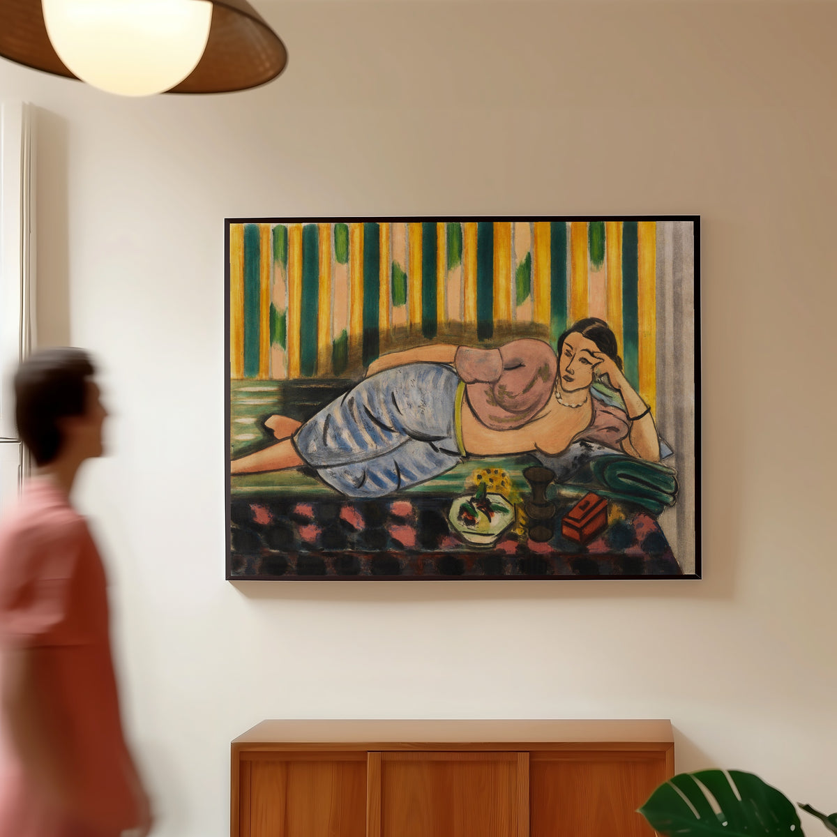 Framed art print of Odalisque with a Red Casket by Henri Matisse, in a slim black frame on a warm wall in a sunlit room