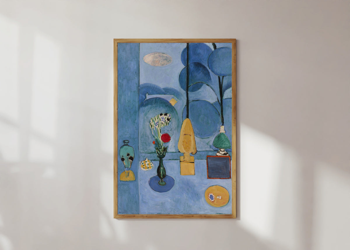 Framed art print of The Blue Window (La Glace sans tain) by Henri Matisse, in a light wood frame on a sunlit white wall