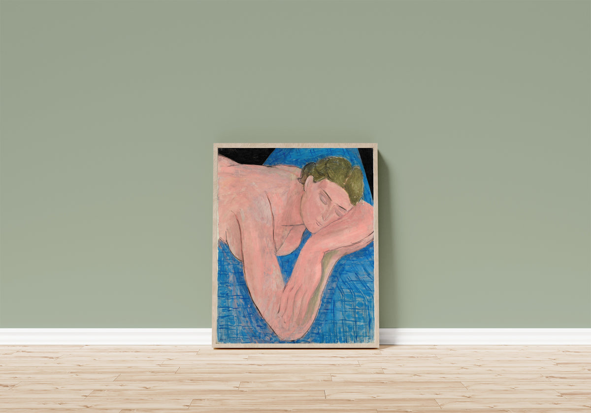 Framed art print of The Dream (Le Rêve) by Henri Matisse, in a light wood frame leaning on a sage green wall above a wooden floor