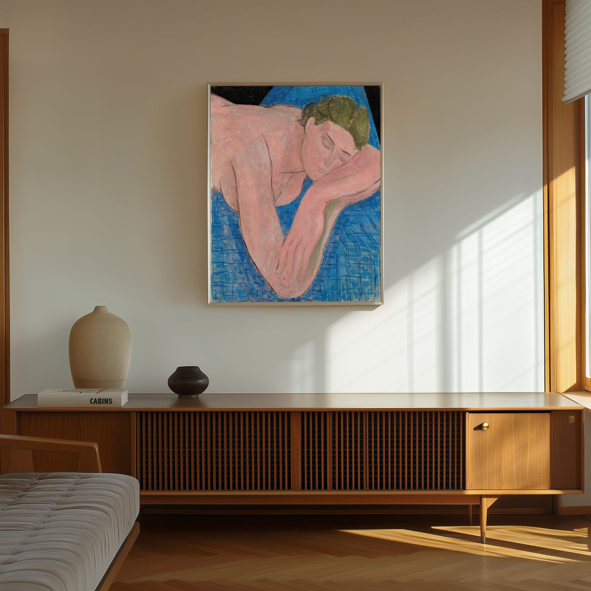 Framed art print of The Dream (Le Rêve) by Henri Matisse, in a thin light frame on a sunlit wall above a wooden sideboard