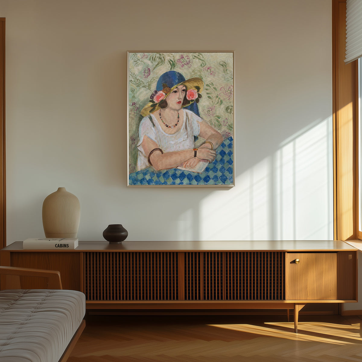 Framed art print of Woman with a Flowered Hat by Henri Matisse, in a thin light frame on a sunlit wall above a wooden sideboard