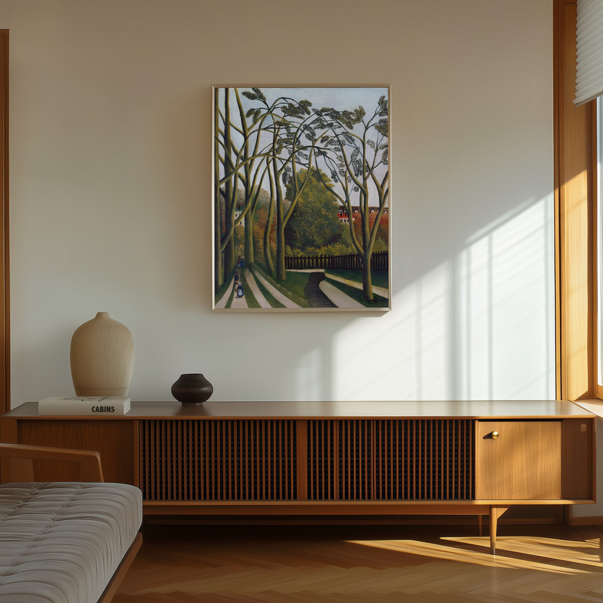 Framed art print of The Banks of the Bièvre near Bicêtre by Henri Rousseau, in a thin light frame on a sunlit wall above a wooden sideboard