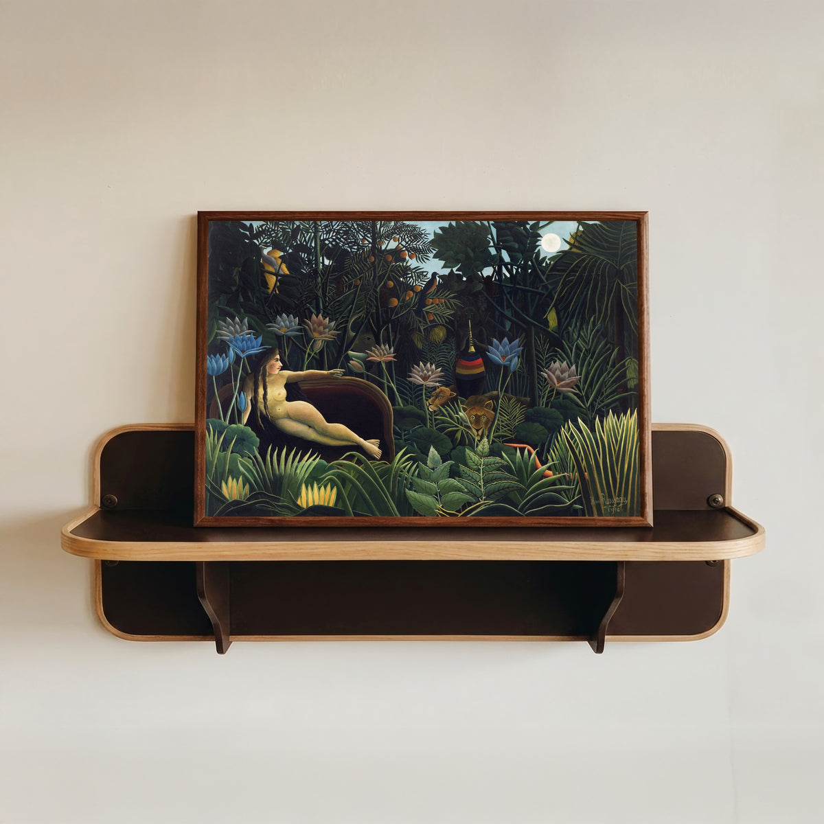 Framed art print of The Dream by Henri Rousseau, in a dark wood frame resting on a wall shelf