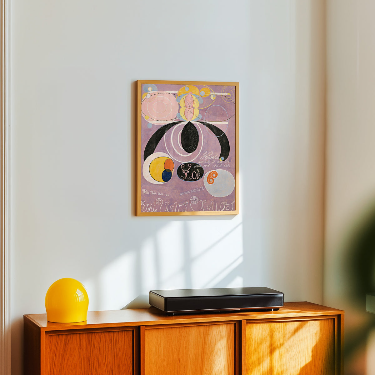 Framed art print of The Ten Largest, No. 6 by Hilma af Klint, in a light wood frame on a white wall above an orange sideboard