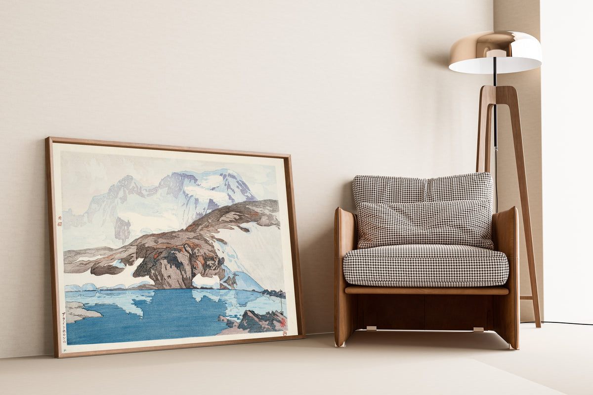 Framed art print of Breithorn by Hiroshi Yoshida, leaning against a wall beside an armchair and a floor lamp