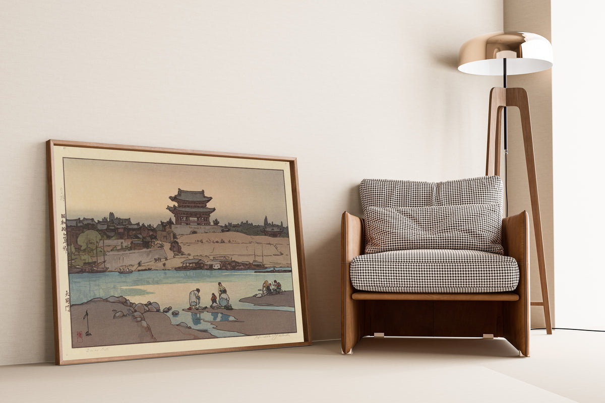 Framed art print of Daidomon (Taedong Gate), Pyongyang by Hiroshi Yoshida, leaning against a wall beside an armchair and a floor lamp
