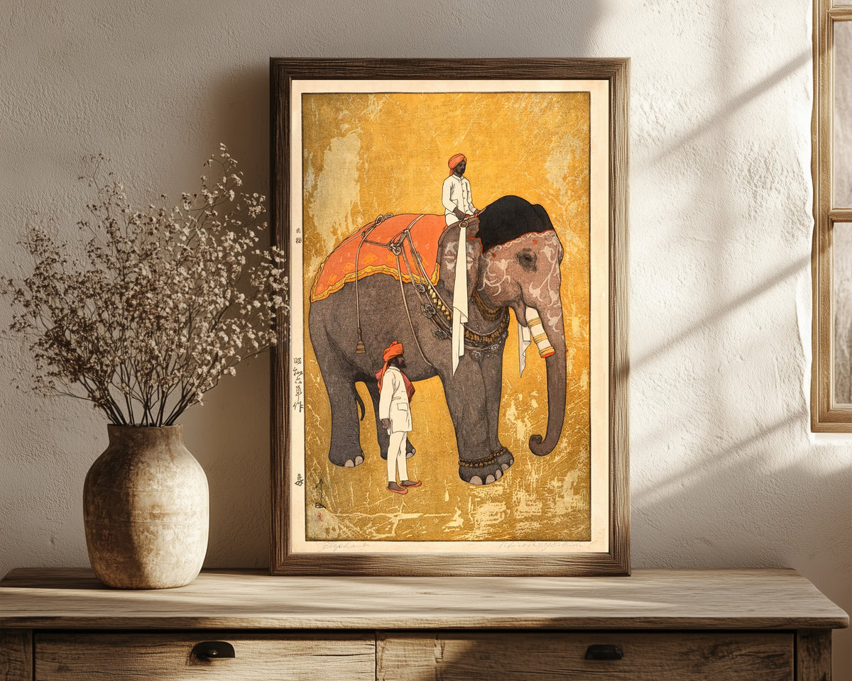 Framed art print of Elephant and Rider by Hiroshi Yoshida, in a dark wood frame leaning on a rustic console beside dried flowers