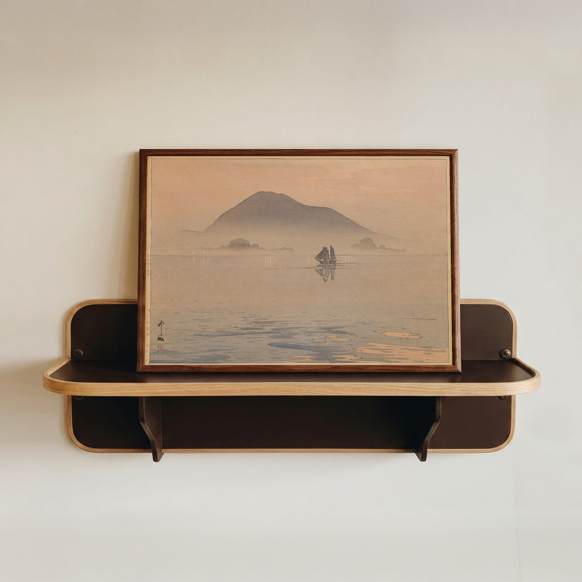 Framed art print of Evening After Rain, Inland Sea by Hiroshi Yoshida, in a dark wood frame resting on a wall shelf