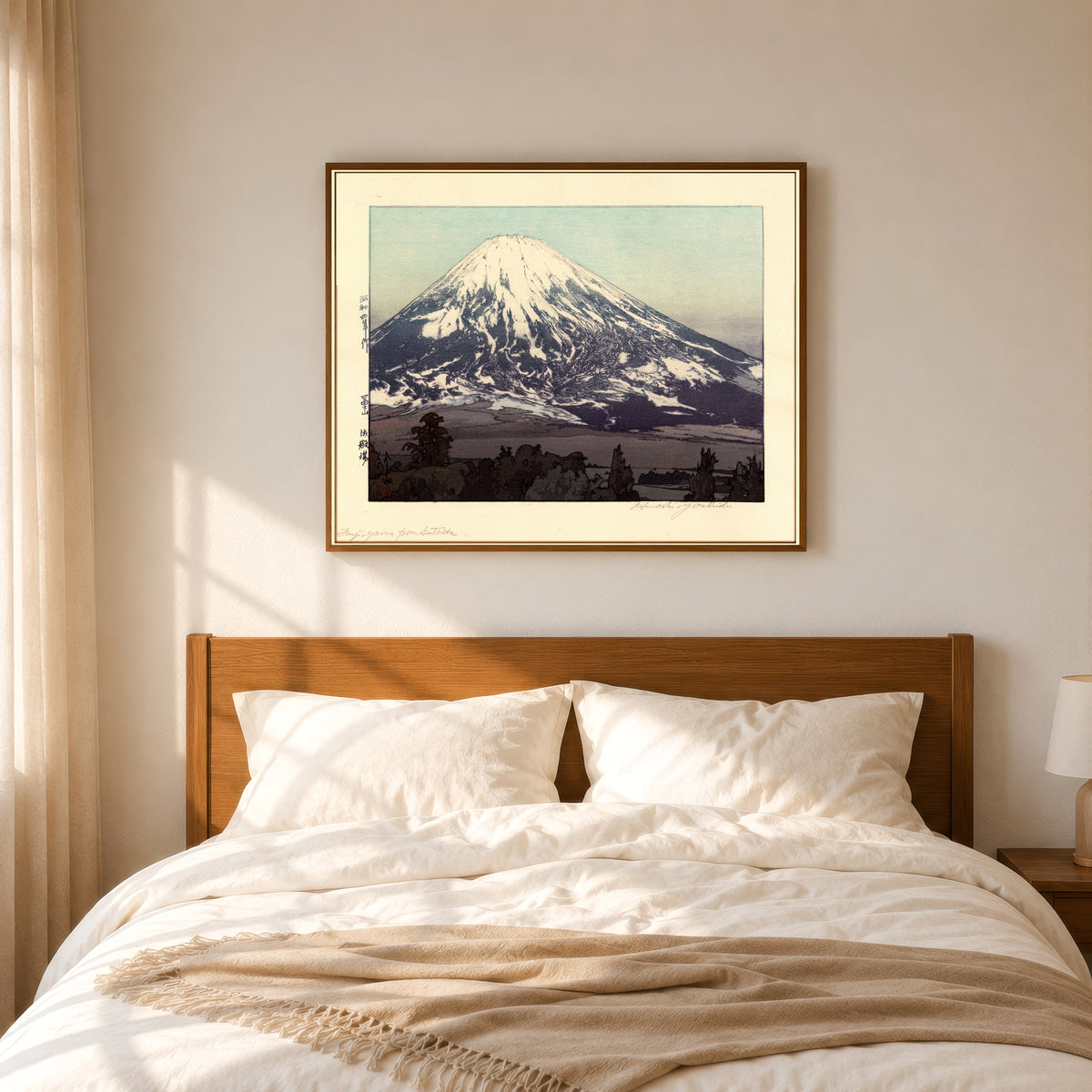 Framed art print of Fujiyama from Gotemba by Hiroshi Yoshida, in a slim wood frame above a bed in a sunlit bedroom