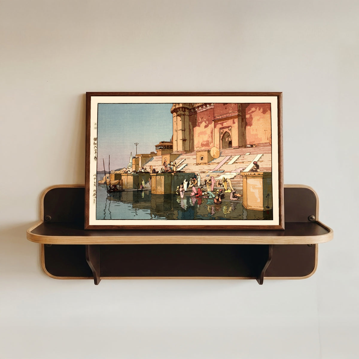 Framed art print of Ghat in Benares, India by Hiroshi Yoshida, in a dark wood frame resting on a wall shelf