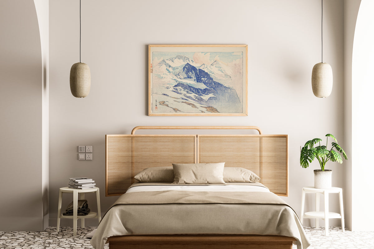 Framed art print of Jungfrau by Hiroshi Yoshida, above a cane-headboard bed