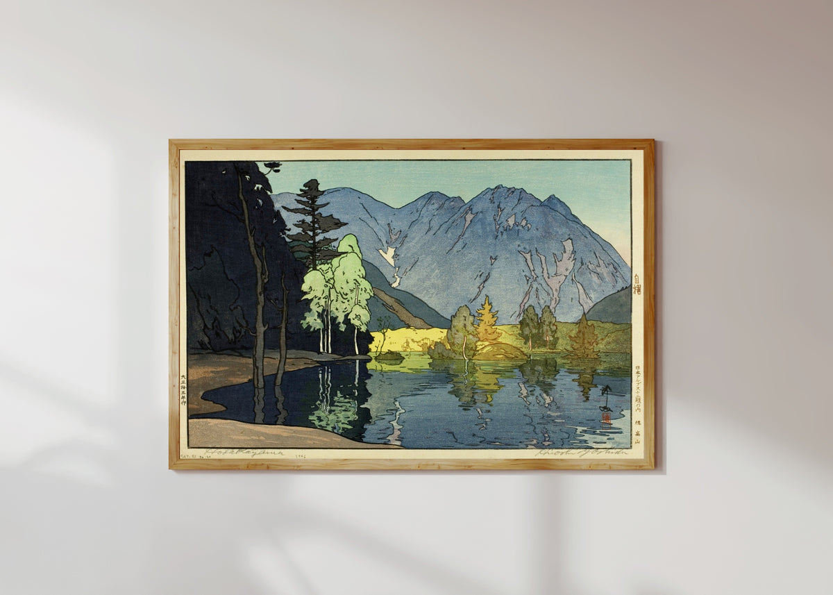 Framed art print of Mount Hodaka by Hiroshi Yoshida, in a light wood frame on a sunlit white wall