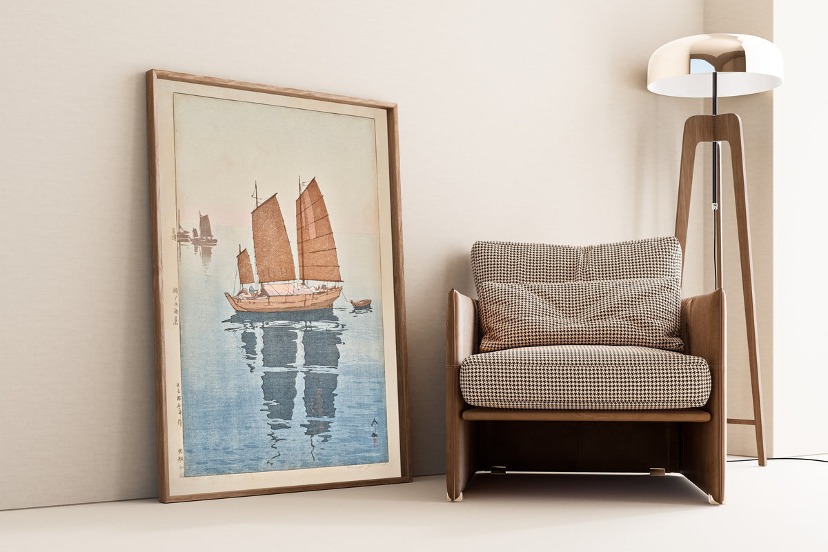 Framed art print of Sailing Boats, Forenoon by Hiroshi Yoshida, leaning against a wall beside an armchair and a floor lamp