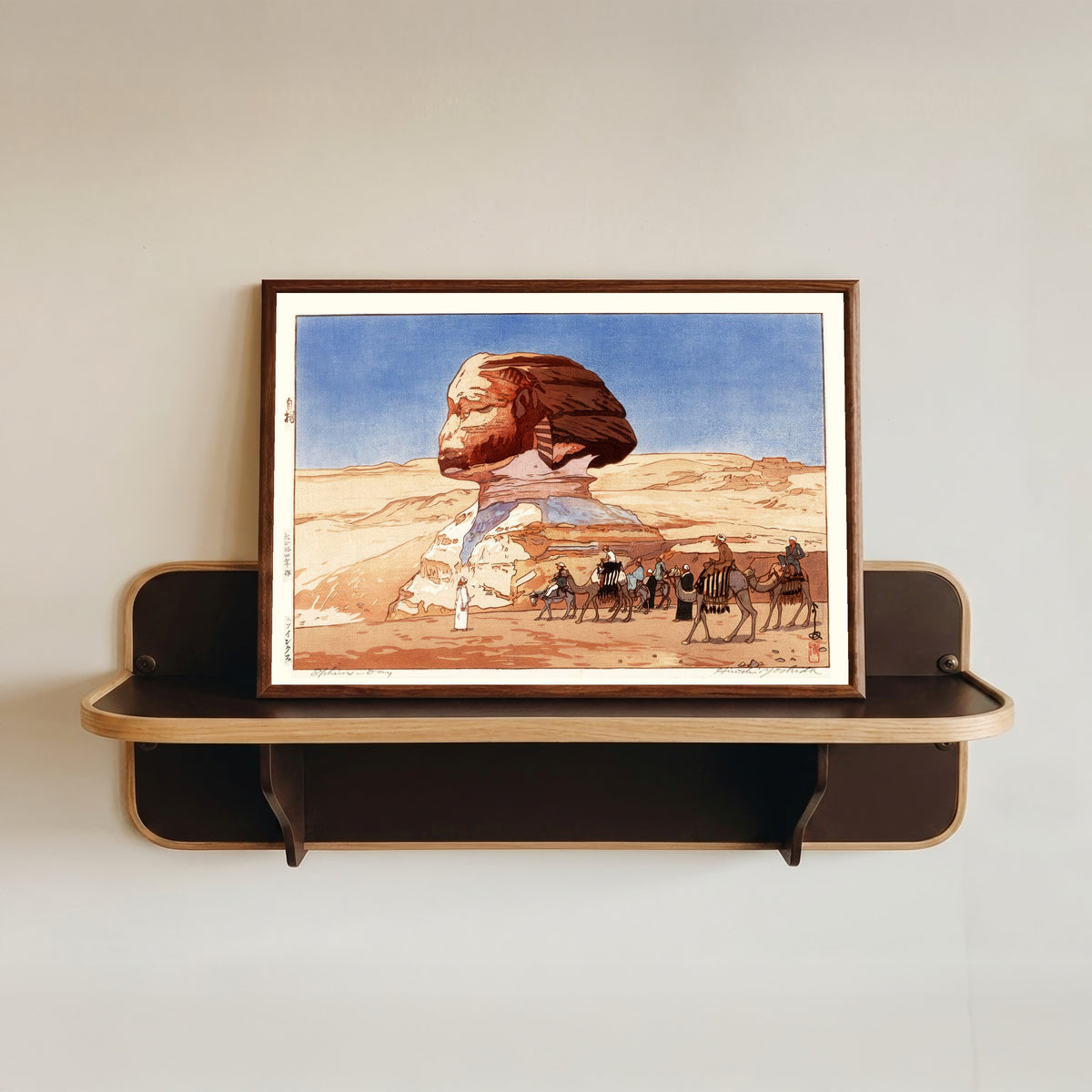 Framed art print of Sphinx at Day by Hiroshi Yoshida, in a dark wood frame resting on a wall shelf