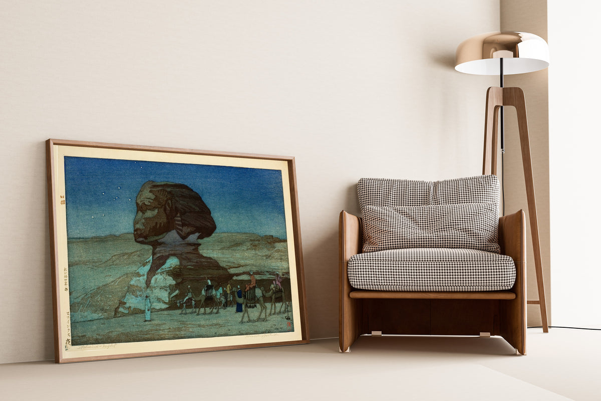 Framed art print of Sphinx at Night by Hiroshi Yoshida, leaning against a wall beside an armchair and a floor lamp