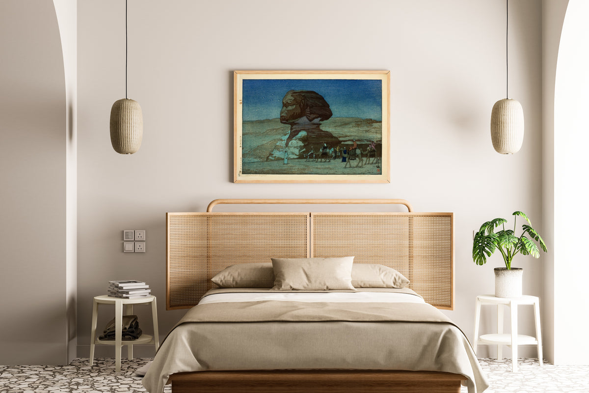 Framed art print of Sphinx at Night by Hiroshi Yoshida, above a cane-headboard bed