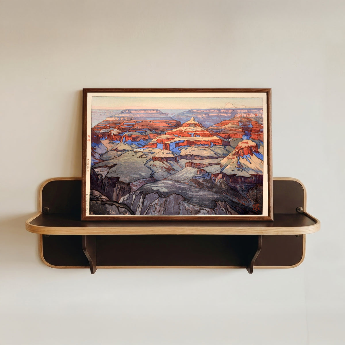 Framed art print of The Grand Canyon by Hiroshi Yoshida, in a dark wood frame resting on a wall shelf
