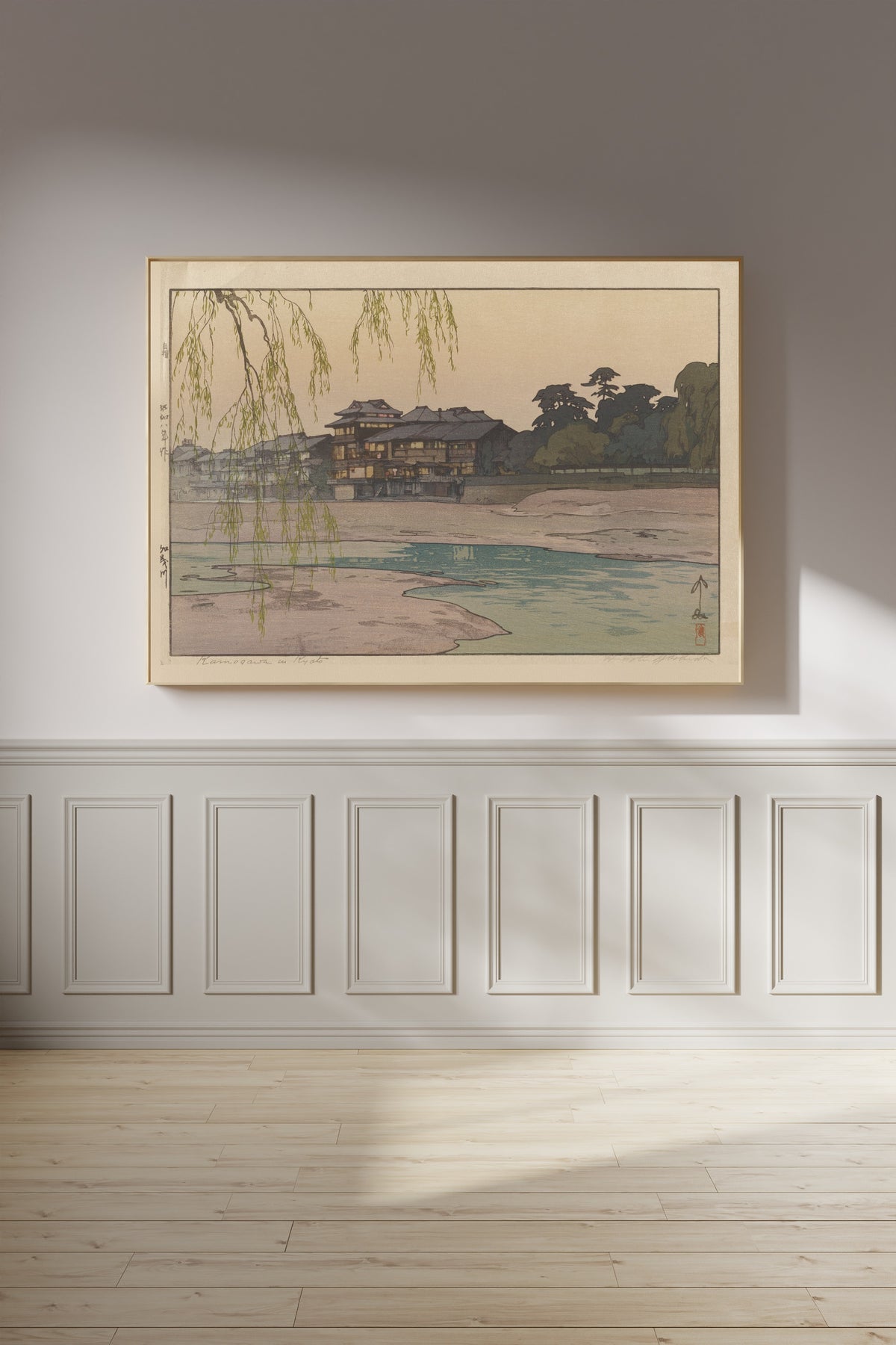 Framed art print of The Kamo River by Hiroshi Yoshida, on a panelled wall in afternoon light