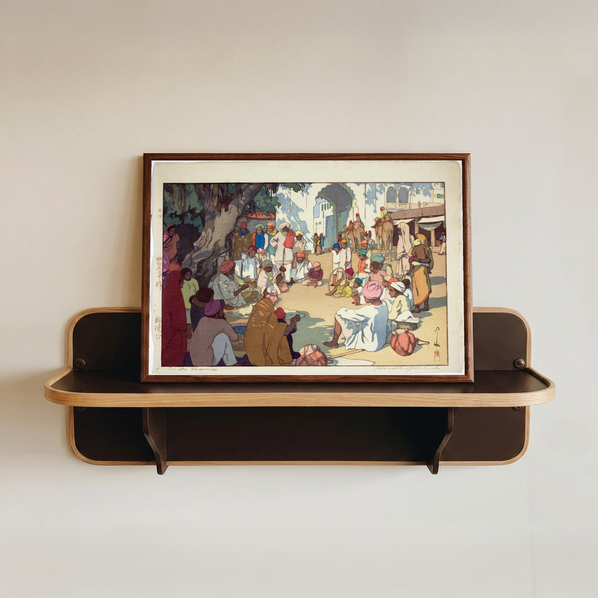 Framed art print of Snake Charmers by Hiroshi Yoshida, in a dark wood frame resting on a wall shelf