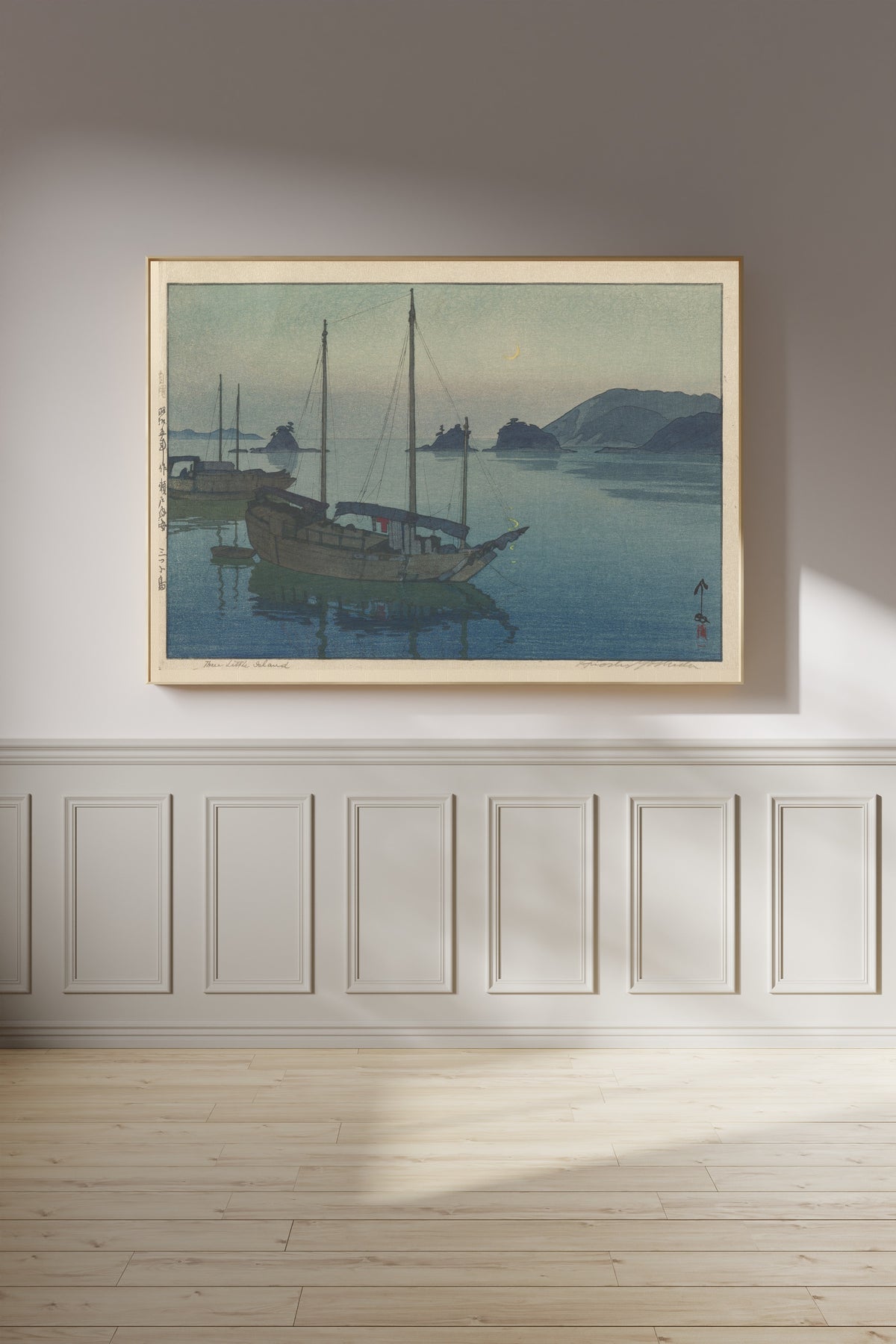 Framed art print of Three Little Islands by Hiroshi Yoshida, on a panelled wall in afternoon light