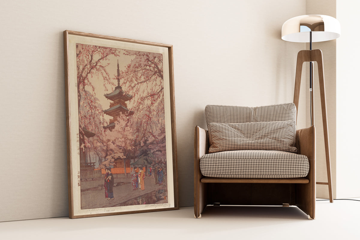 Framed art print of Ueno Park by Hiroshi Yoshida, leaning against a wall beside an armchair and a floor lamp
