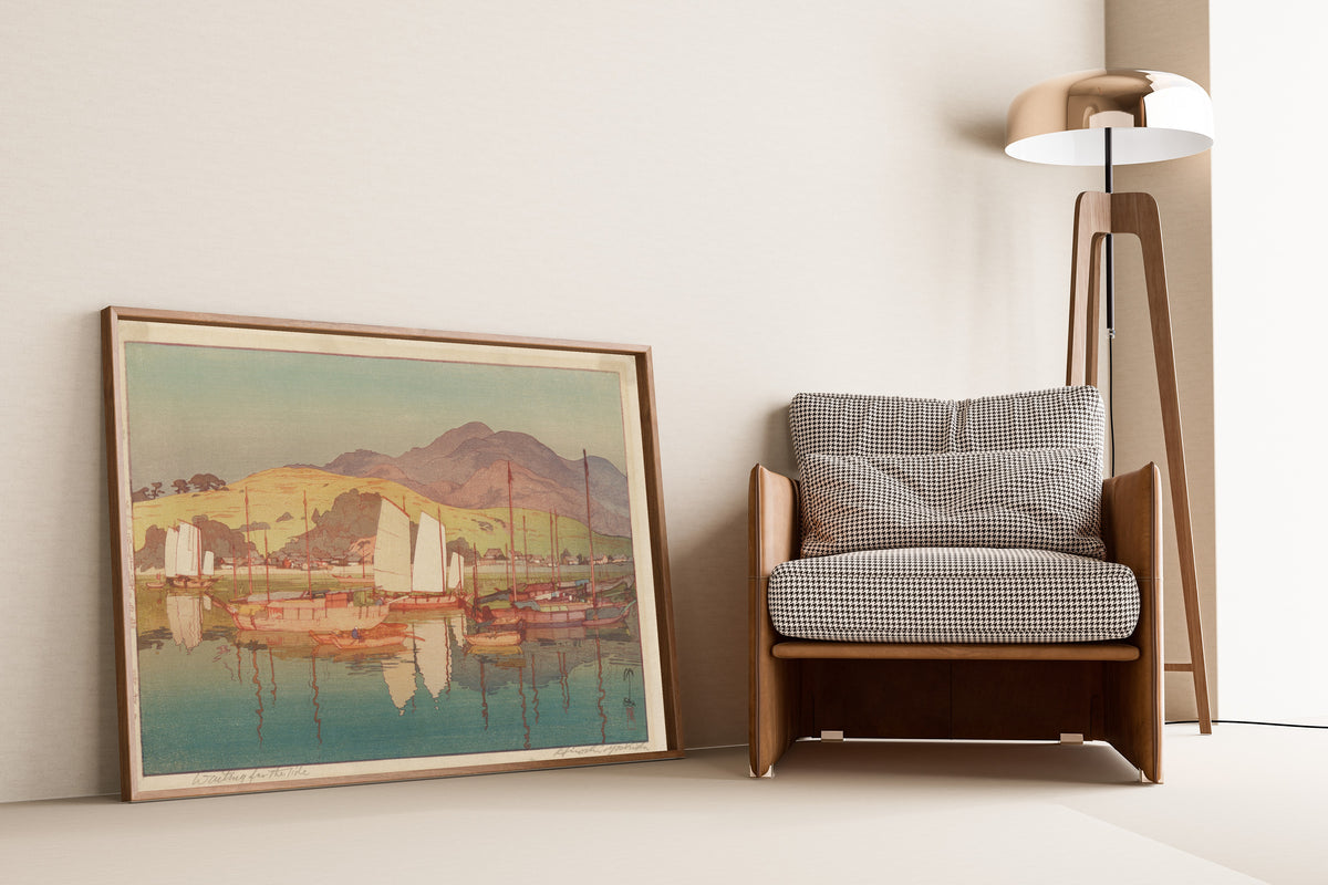 Framed art print of Waiting for the Tide by Hiroshi Yoshida, leaning against a wall beside an armchair and a floor lamp