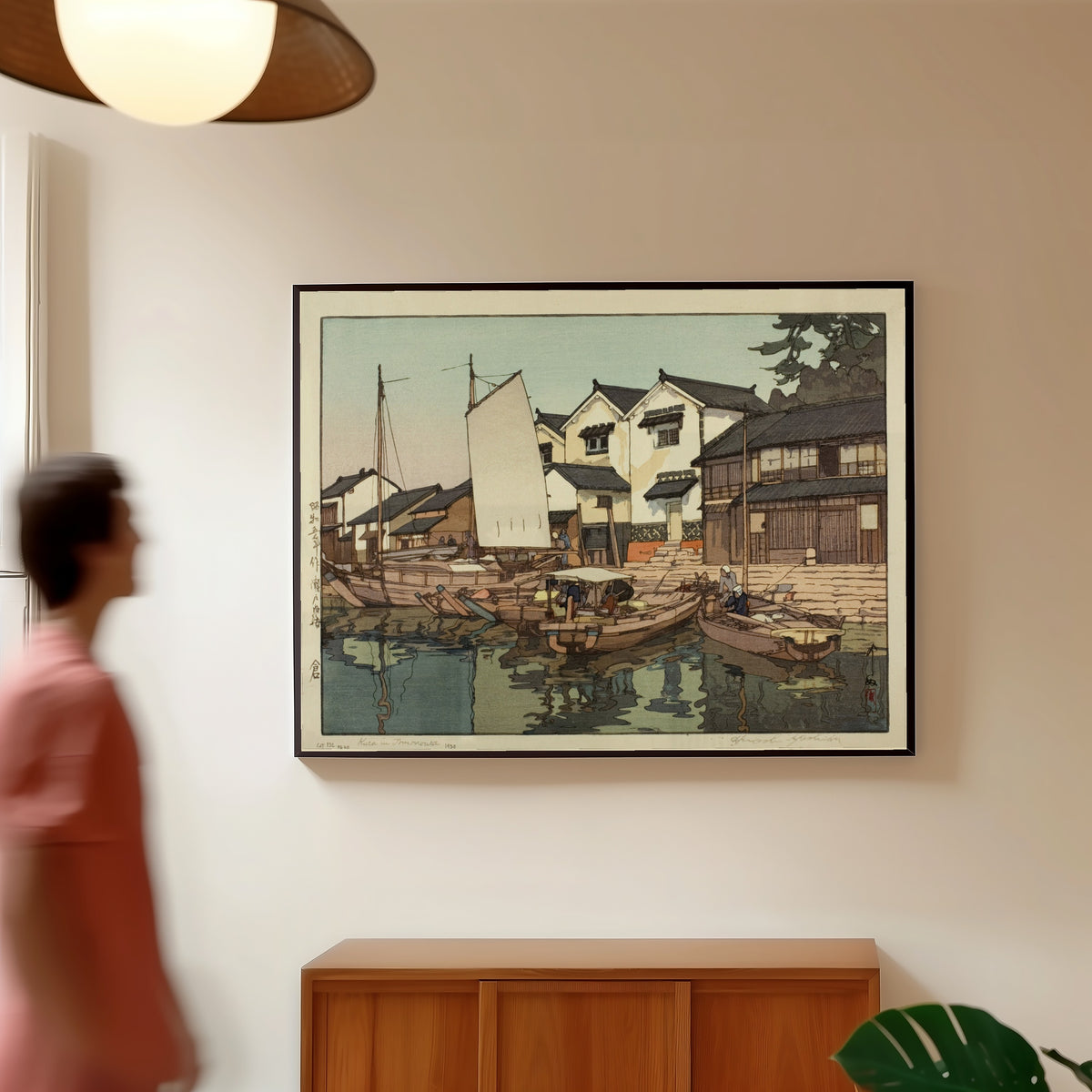 Framed art print of Tomonoura Warehouse by Hiroshi Yoshida, in a slim black frame on a warm wall in a sunlit room