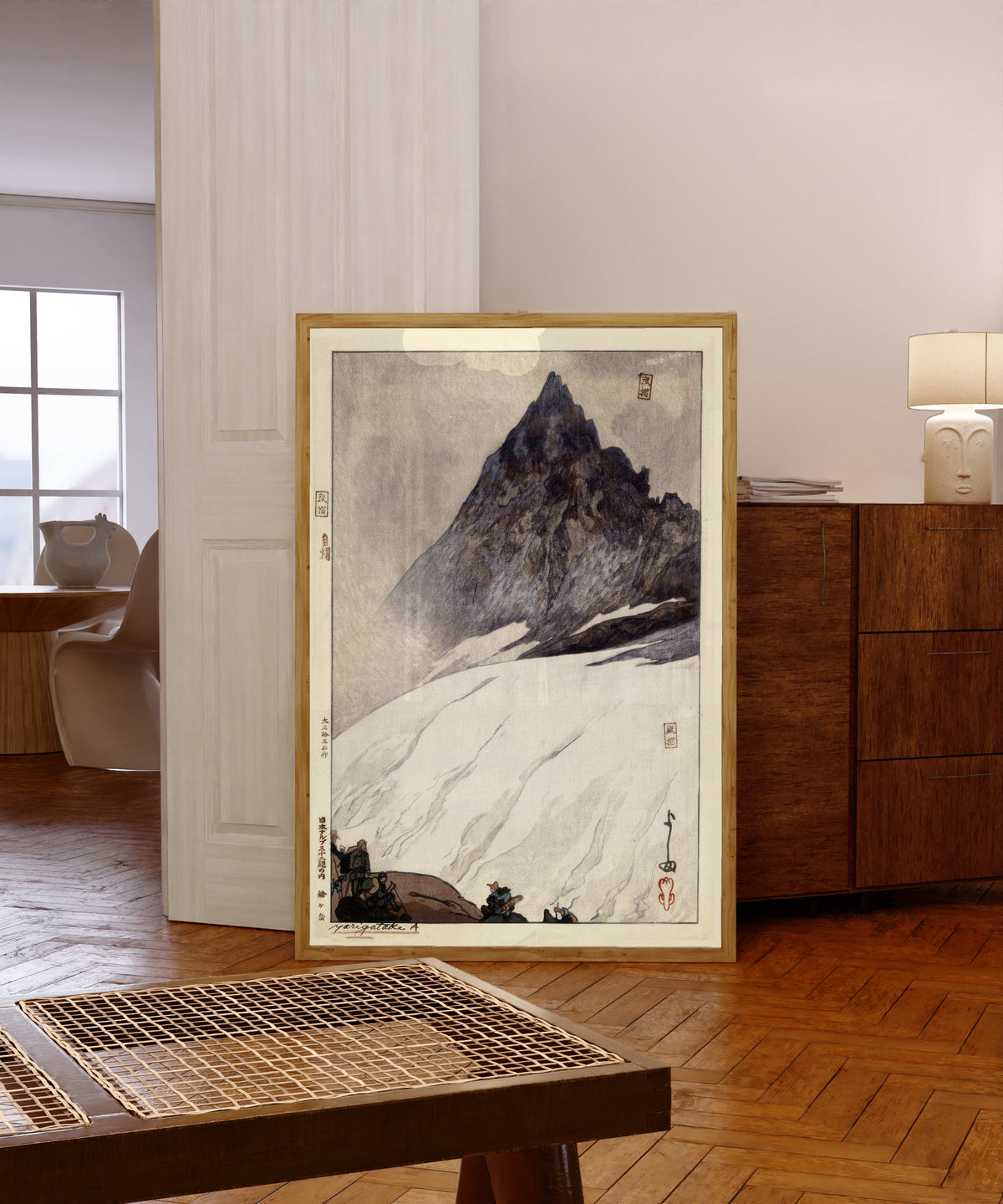 Framed art print of Yarigadake by Hiroshi Yoshida, in a light wood frame leaning in a warm room with a parquet floor