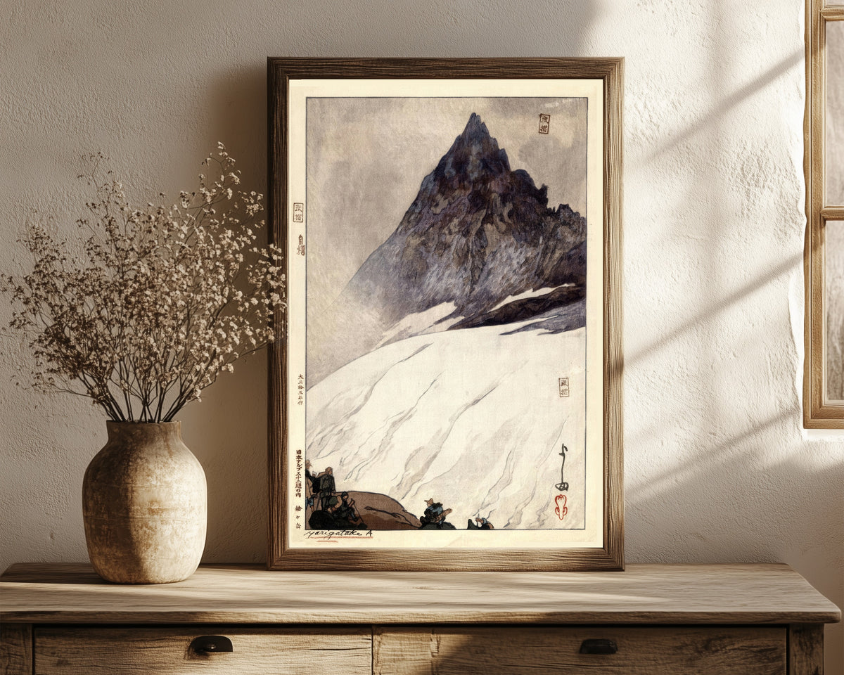 Framed art print of Yarigadake by Hiroshi Yoshida, in a dark wood frame leaning on a rustic console beside dried flowers