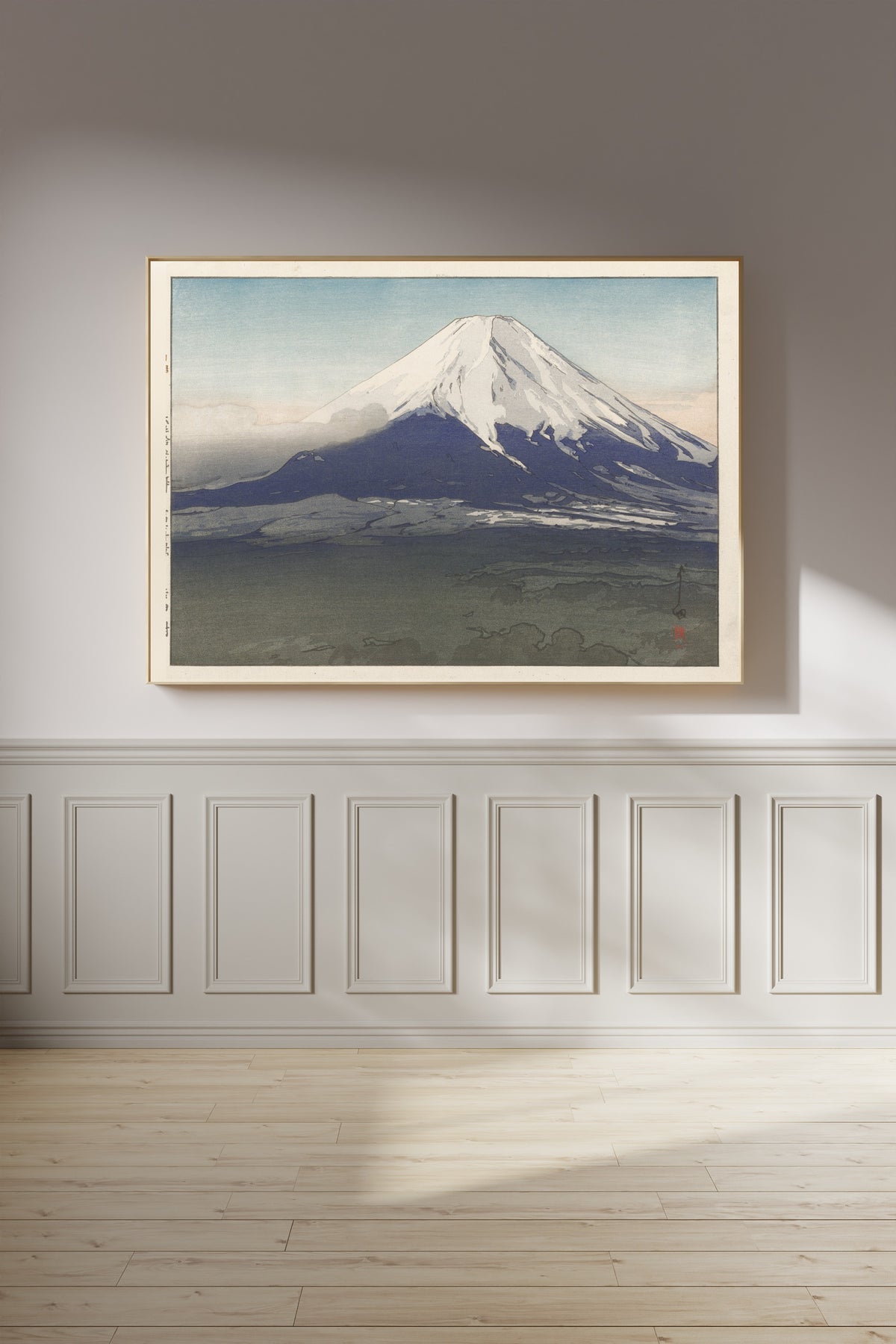Framed art print of Yoshida Village by Hiroshi Yoshida, on a panelled wall in afternoon light
