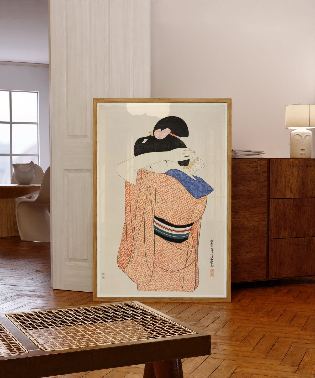 Framed art print of The Long Undergarment by Ito Shinsui, in a light wood frame leaning in a warm room with a parquet floor