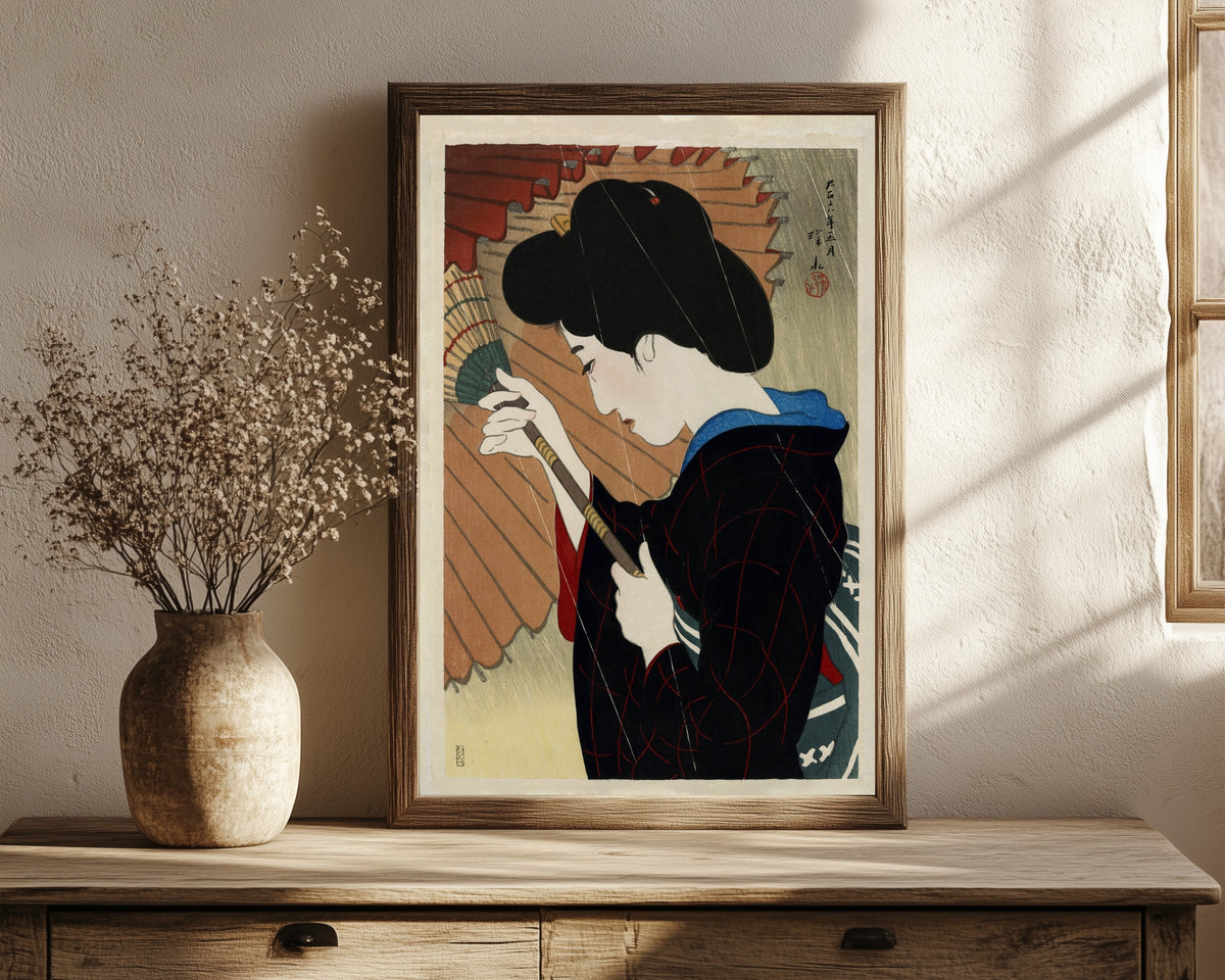 Framed art print of Passing Rain by Ito Shinsui, in a dark wood frame leaning on a rustic console beside dried flowers