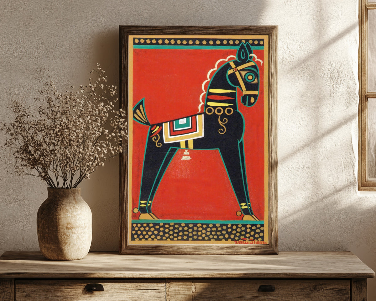 Framed art print of Black Horse (Kalo Ghora) by Jamini Roy, in a dark wood frame leaning on a rustic console beside dried flowers