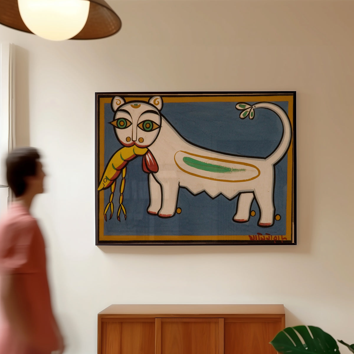 Framed art print of Cat and Shrimp by Jamini Roy, in a slim black frame on a warm wall in a sunlit room