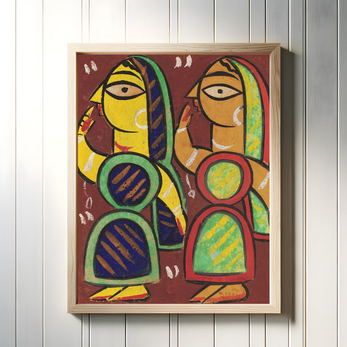 Framed art print of Untitled by Jamini Roy, in a light wood frame on a white panelled wall