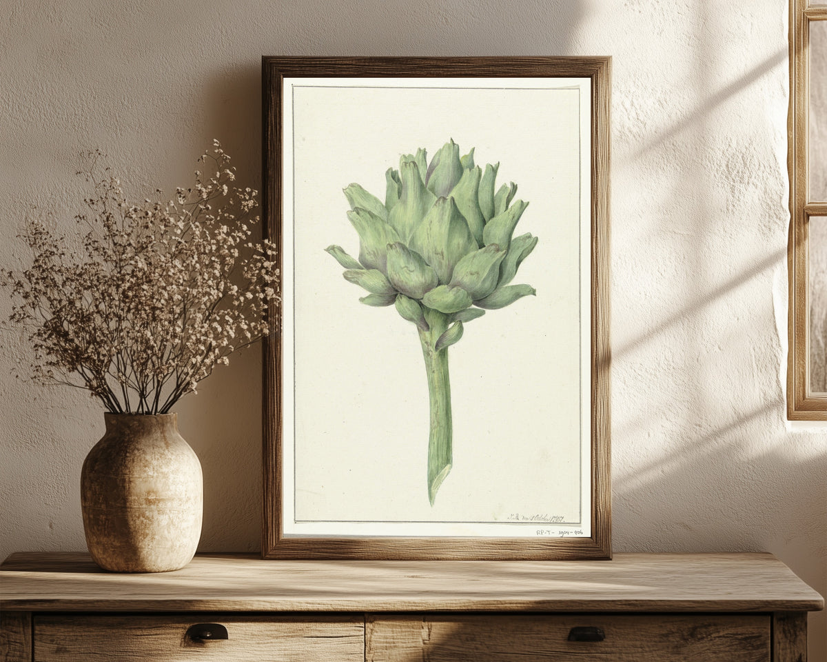 Framed art print of Artisjok (Artichoke) by Jean Bernard, in a dark wood frame leaning on a rustic console beside dried flowers