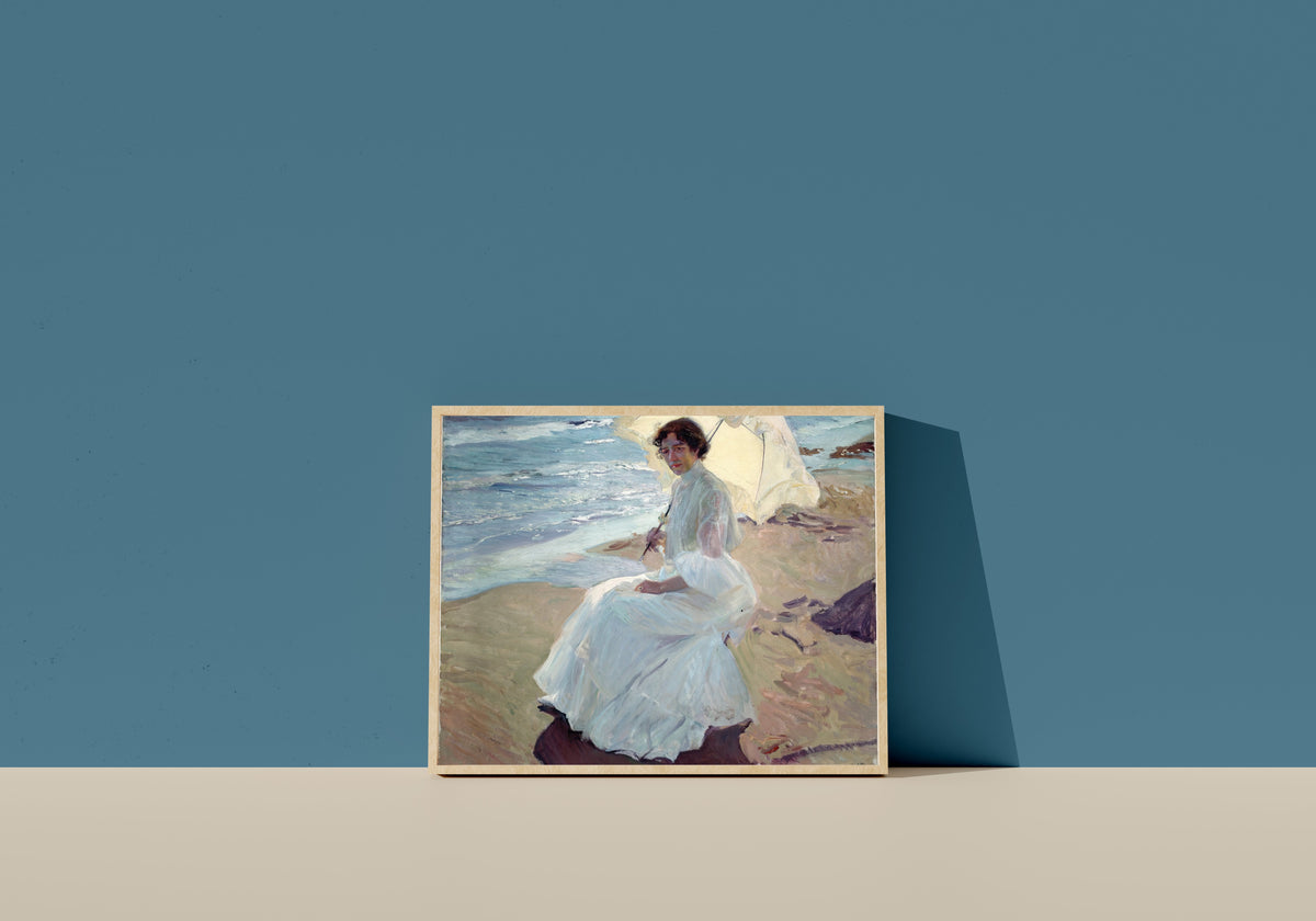 Framed art print of Clotilde on the Beach by Joaquín Sorolla, in a light wood frame leaning on a blue wall