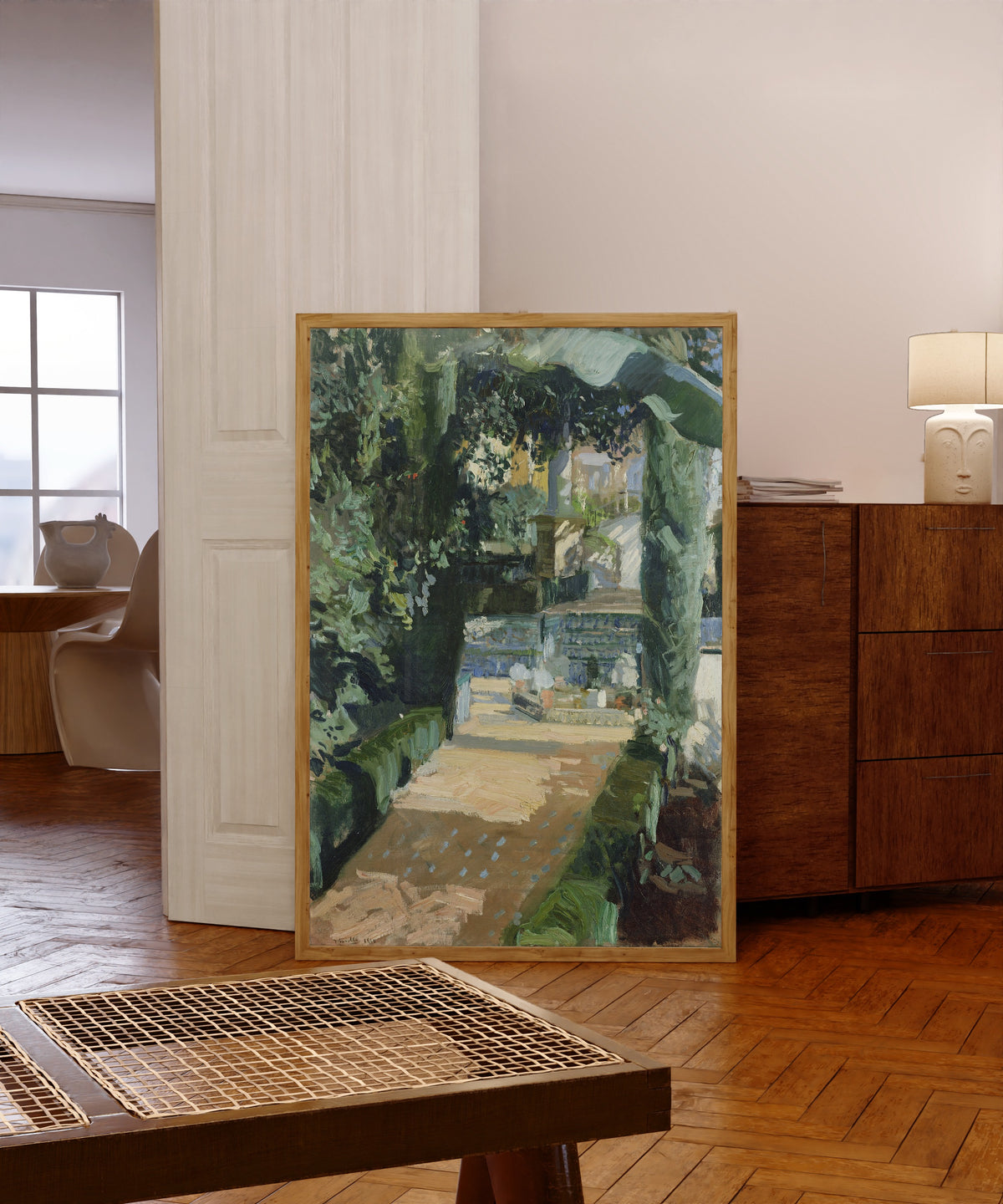 Framed art print of Court of the Dances, Alcázar of Seville by Joaquín Sorolla, in a light wood frame leaning in a warm room with a parquet floor