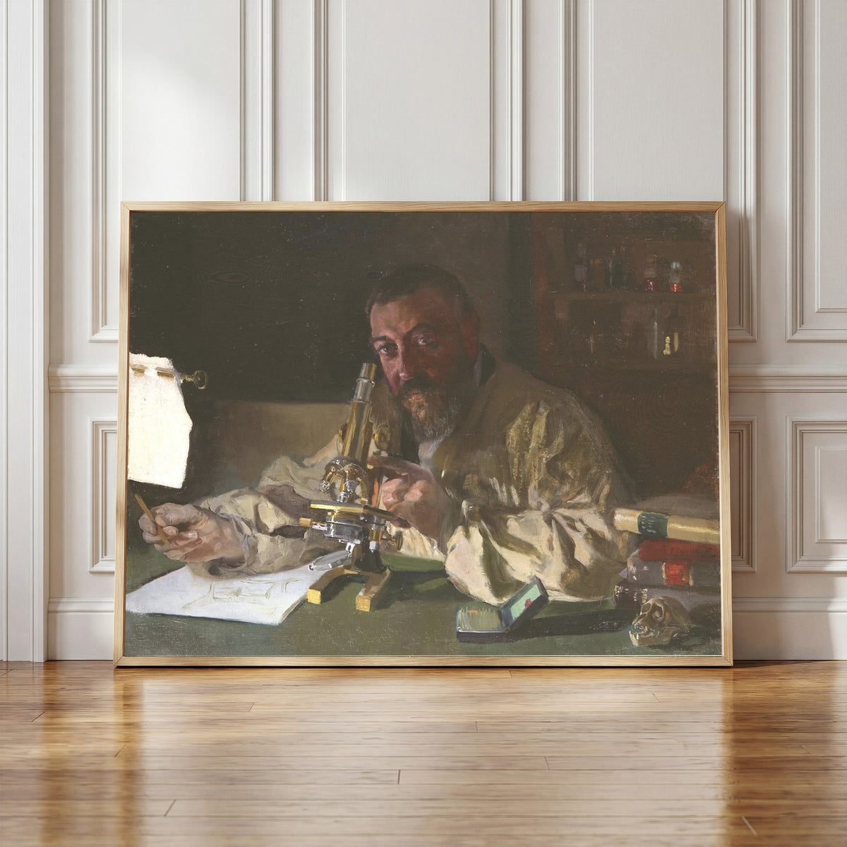 Framed art print of Dr. Simarro at the Microscope by Joaquín Sorolla, in a light wood frame leaning against a panelled white wall
