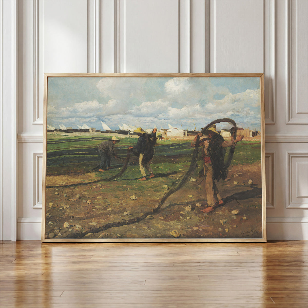 Framed art print of Fishermen with their Nets by Joaquín Sorolla, in a light wood frame leaning against a panelled white wall