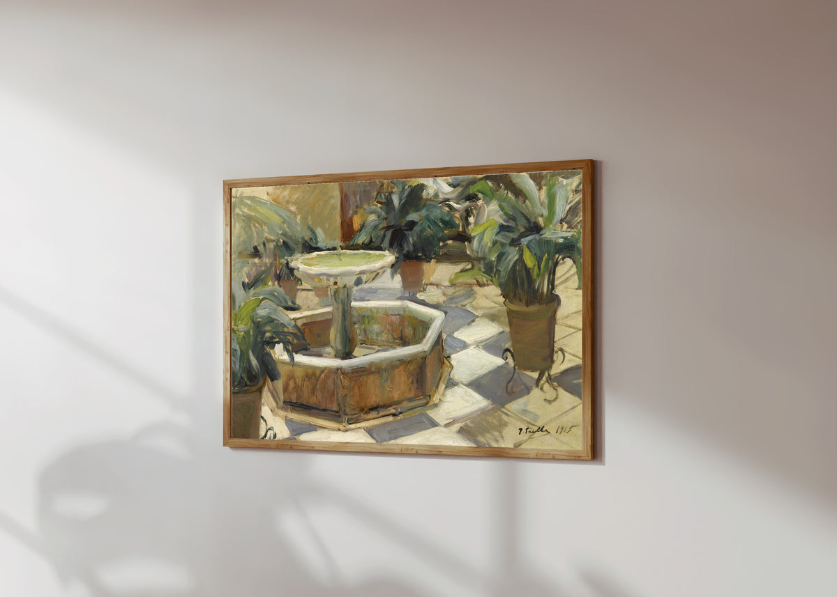 Framed art print of Fountain in a Sevillian Courtyard by Joaquín Sorolla, in a light wood frame on a sunlit white wall, seen at a slight angle
