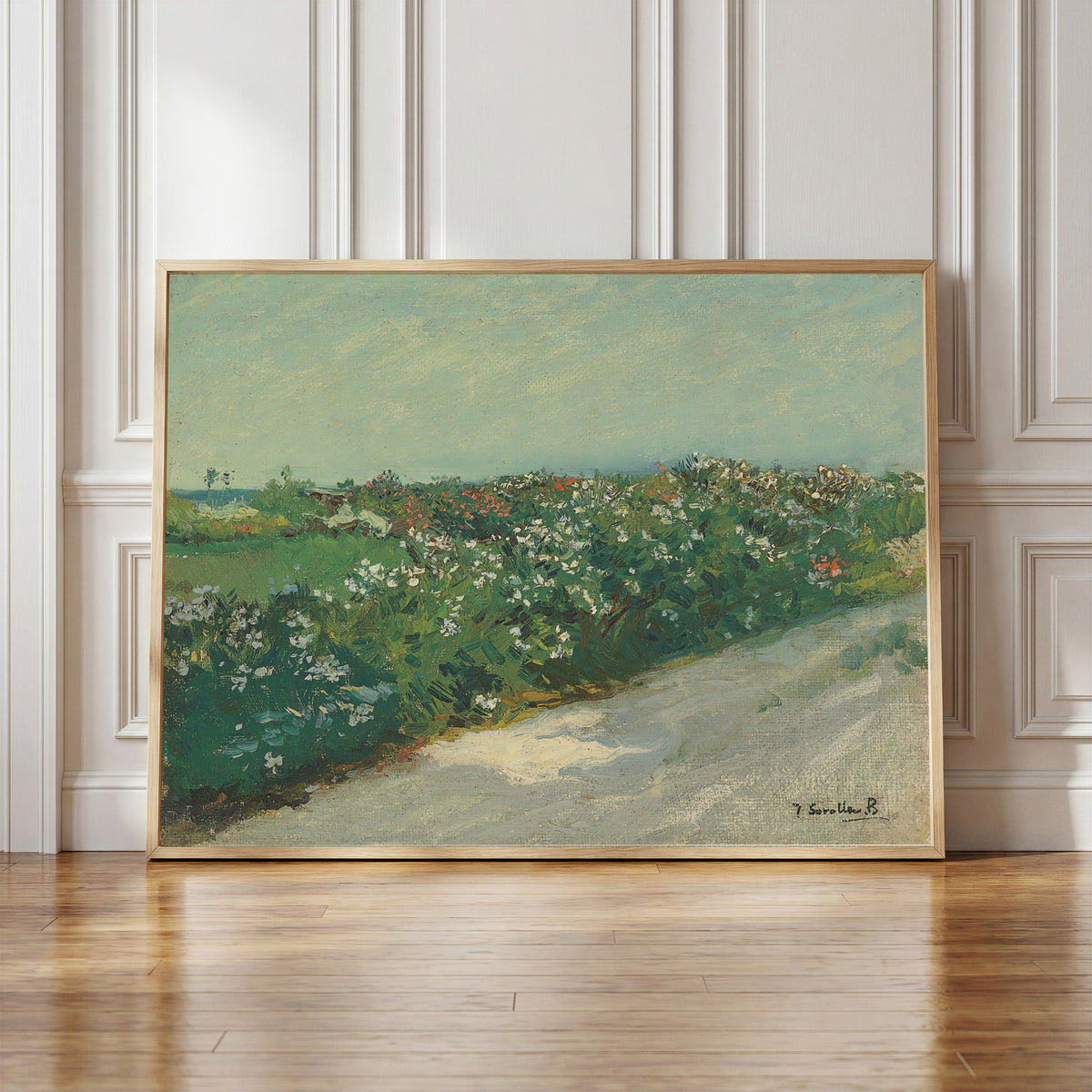 Framed art print of Malvarrosa by Joaquín Sorolla, in a light wood frame leaning against a panelled white wall