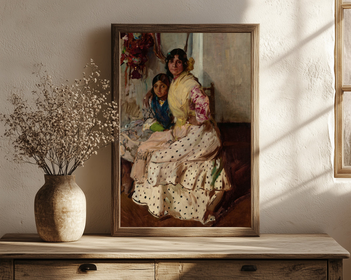 Framed art print of Pepilla the Gypsy and Her Daughter by Joaquín Sorolla, in a dark wood frame leaning on a rustic console beside dried flowers
