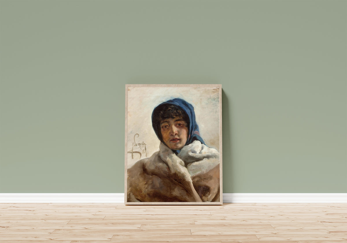 Framed art print of Portrait of a Woman in a Blue Headscarf by Joaquín Sorolla, in a light wood frame leaning on a sage green wall above a wooden floor
