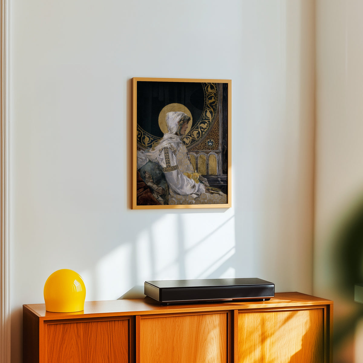 Framed art print of Saint in Prayer (Santa en oración) by Joaquín Sorolla, in a light wood frame on a white wall above an orange sideboard